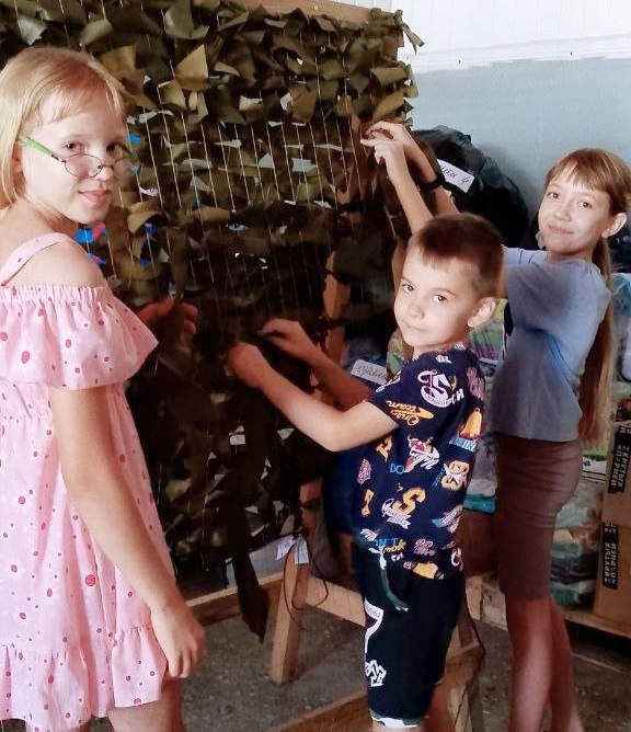 Дети вкладывают свой труд в плетение маскировочных сетей